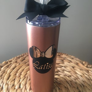 Puede incluir: Un vaso de acero inoxidable color oro rosa con un lazo negro y un dise&ntilde;o de Minnie Mouse negro y dorado con el nombre "Latisa" en &eacute;l.