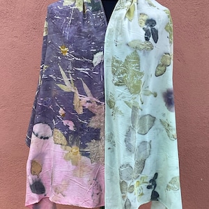 Pu&ograve; includere: Una sciarpa lunga e rettangolare con un motivo floreale rosa chiaro e viola da un lato e un motivo floreale verde chiaro dall'altro.