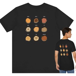 May include: Black t-shirt featuring a graphic of various tree cross-sections, including names like Cherry, Walnut, and Ash. The design is repeated on the back of the shirt. The shirt is made of a soft material.
