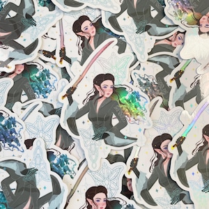 May include: A collection of holographic stickers featuring an elf character holding a sword. The stickers have a blue and white design with a floral pattern.