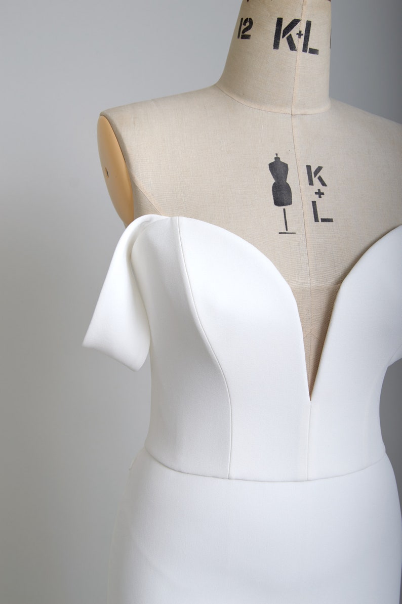 K&ouml;nnte beinhalten: Ein wei&szlig;es, schulterfreies Kleid mit einem Herz-Ausschnitt und einer figurbetonten Silhouette.