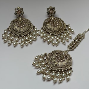 May include: A set of antique gold-toned earrings and a headpiece. The earrings and headpiece feature intricate filigree designs, small clear stones, and dangling faux pearls. The jewelry is likely for a special occasion.