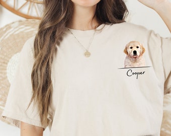 May include: A beige t-shirt with a graphic of a golden retriever puppy peeking out of a pocket. The text "Cooper" is printed below the puppy.