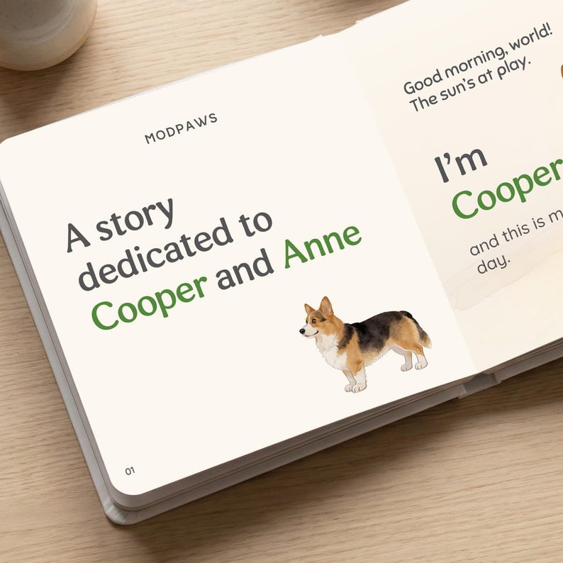 May include: An open book with the text "A story dedicated to Cooper and Anne" and "Good morning, world! The sun's at play." A watercolor illustration of a corgi dog is also present. The book is on a light-colored surface.