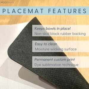 May include: A black placemat with the text "PLACEMAT FEATURES". The placemat has a non-skid black rubber backing and is easy to clean. It features a moisture-wicking surface and a permanent custom print using dye sublimation.