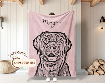 May include: A soft, light pink fleece blanket featuring a black line-art illustration of a dog's face centered on the fabric. The name Morgan is printed in a black cursive script above the dog illustration. The blanket has a smooth texture.