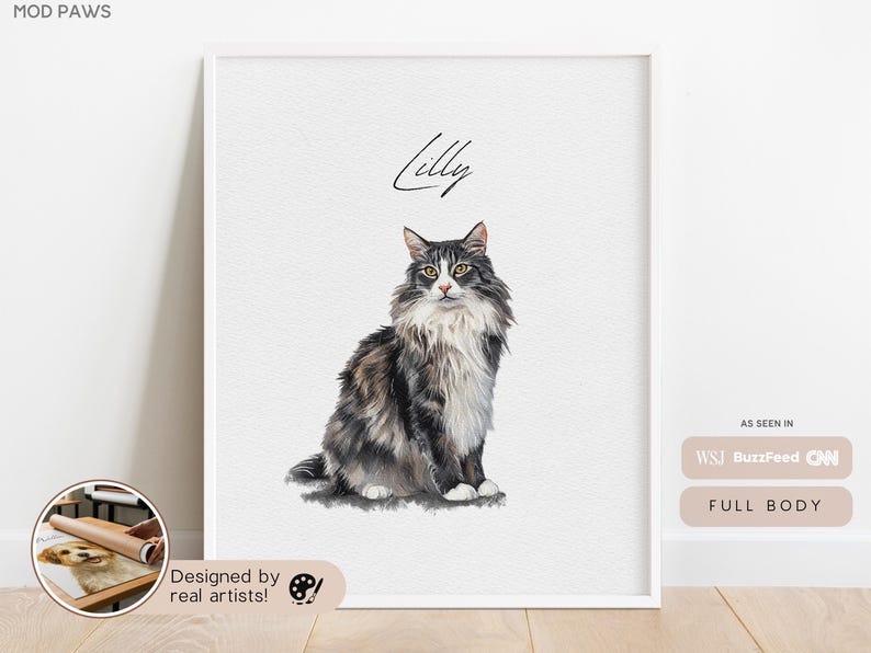 May include: A framed watercolor portrait of a cat named Lilly. The cat is a fluffy, medium-haired breed with gray, black, and white fur. The artwork is displayed on a white background, with the words "Designed by real artists!" at the bottom.