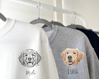 May include: A white sweatshirt featuring a black line-art illustration of a dog with the name Milo printed below, and a gray sweatshirt featuring a full-color illustration of a golden retriever dog with the name LUNA printed below.
