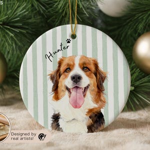 Pode incluir: Enfeite de Natal redondo de cer&acirc;mica com um retrato em aquarela de um c&atilde;o com pelo castanho, branco e preto e uma l&iacute;ngua rosa. O enfeite tem um fundo listrado verde e branco, o nome "Hunter" e uma pegada.