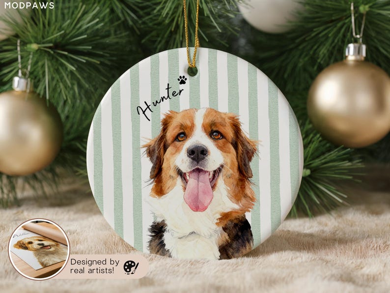 Pode incluir: Enfeite de Natal redondo de cer&acirc;mica com um retrato em aquarela de um c&atilde;o com pelo castanho, branco e preto e uma l&iacute;ngua rosa. O enfeite tem um fundo listrado verde e branco, o nome "Hunter" e uma pegada.