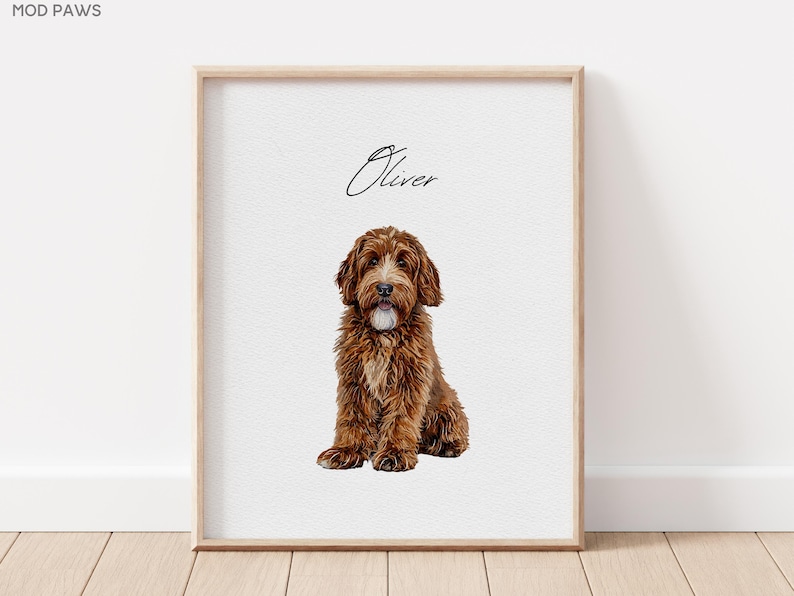 Op de afbeelding: Een ingelijste print met een bruine hond met een pluizige vacht, zittend tegen een witte achtergrond. De naam van de hond, "Oliver", staat er in cursief boven. De lijst is licht van hout en de print wordt op een houten vloer getoond.
