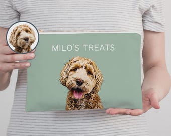 Peut inclure: Une pochette rectangulaire zippée vert sauge avec une illustration personnalisée d'un chien doodle brun doré la langue sortie. Le texte "MILO'S TREATS" est imprimé en blanc au-dessus de l'illustration. Un petit encart circulaire montre le visage du chien.