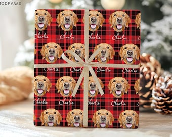 Op de afbeelding: Een rechthoekige geschenkdoos verpakt in rood en zwart geruit papier met een herhalend patroon van golden retriever-gezichten en de naam Charlie in witte schrijfletters. Een gouden lint is in een strik rond het midden van het pakket gebonden.