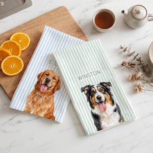 Può includere: Due strofinacci rettangolari con ritratti di cani personalizzati. Uno presenta strisce blu e un golden retriever, l'altro strisce verdi e un pastore australiano con il nome WINSTON stampato nella parte superiore.