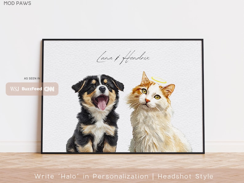 Op de afbeelding: Een ingelijste print met een hond en een kat. De hond is zwart, bruin en wit met zijn tong uit. De kat is wit en oranje met een halo. De tekst "Luna & Hendrix" staat boven de dieren. De print zit in een zwarte lijst.