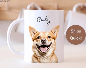 Könnte beinhalten: Ein weißer Keramikbecher mit einer aufgedruckten Illustration eines hellbraun-weißen Hundes, der mit offenem Maul lächelt. Der Name Bailey ist in schwarzer Schreibschrift über dem Kopf des Hundes aufgedruckt. Der Text MODPAWS steht oben links.