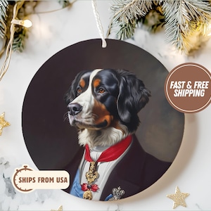 May include: A round ceramic bauble featuring a portrait of a Bernese Mountain Dog wearing a red and blue sash with a gold medal. The dog is depicted in a regal style with a serious expression. The bauble is ideal for dog lovers and collectors.