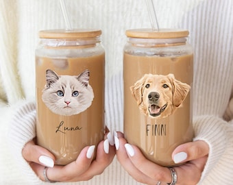 May include: Two clear glass tumblers with bamboo lids and glass straws, each filled with iced coffee. One glass features a portrait of a cat with the name Luna printed below, while the other shows a golden retriever with the name FINN printed below.