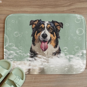 May include: A rectangular bath mat featuring a dog with black, brown, and white fur, surrounded by bubbles. The dog has its tongue out. Two pairs of light green sandals are in the foreground.