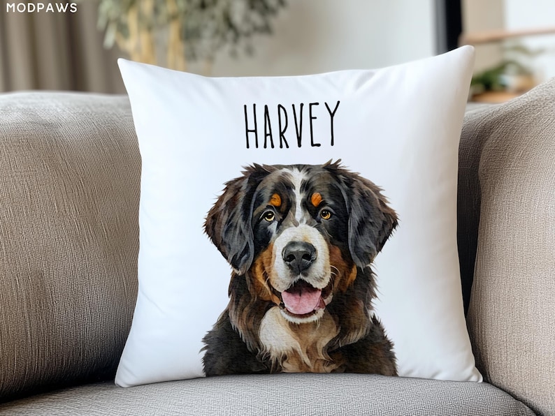 Puede incluir: Coj&iacute;n cuadrado blanco con un retrato de acuarela de un perro de monta&ntilde;a bern&eacute;s. El perro tiene pelo negro, marr&oacute;n y blanco, con el nombre "HARVEY" impreso en negro encima. El coj&iacute;n est&aacute; sobre un sof&aacute; gris.
