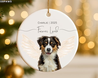 Könnte beinhalten: Runder weißer Keramik-Weihnachtsschmuck mit goldenem Aufhänger. Er zeigt eine Hundeillustration mit Engelsflügeln und dem Text "Charlie | 2025 Forever Loved". Der Hund hat braunes, schwarzes und weißes Fell.