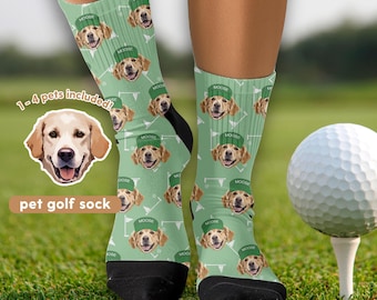 Può includere: Calzini da golf verde chiaro con un motivo ripetuto di un golden retriever con un cappello verde con la scritta "MOOSE". I calzini hanno talloni e dita neri. Una pallina da golf è su un tee nell'erba.