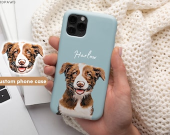 Op de afbeelding: Een lichtblauwe telefoonhoes met een aangepaste illustratie van een bruine en witte hond met de naam "Harlow" in wit op de hoes gedrukt.