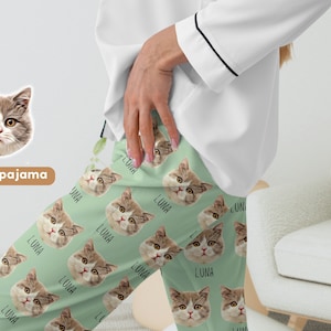 May include: Custom pajama pants with a green background and a repeated pattern of a cat's face with the name "Luna" printed below each cat. The cat's face is brown, white, and black.