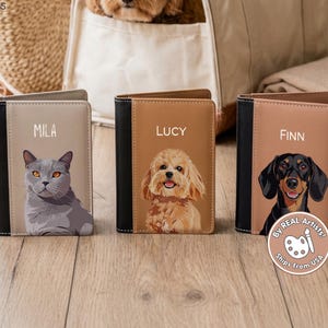 May include: Three personalized pet passport holders. Each features a different pet portrait: a gray cat named Mila, a golden doodle named Lucy, and a dachshund named Finn. The holders have black spines and are labeled with the pet's name.