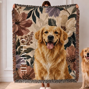 May include: A woven throw blanket featuring a portrait of a golden retriever dog centered against a floral background with muted tones of brown, cream, and green. The name CHARLIE is printed vertically in white capital letters on the left side.