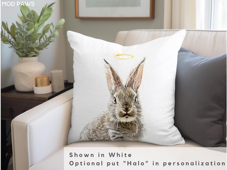 May include: White throw pillow with a watercolor illustration of a gray rabbit with a gold halo. The text "Shown in White" and "Optional put "Halo" in personalization" is below the image.