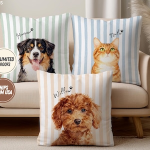 May include: Three decorative throw pillows with pet portraits on a beige sofa. The pillows feature a dog, a cat, and a dog, each with a name above the image. The pillows have vertical striped backgrounds in green, blue, and beige.