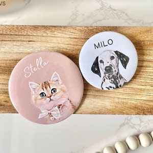 May include: Two round, personalised pet portrait mirrors. One mirror is pink with a cat named Stella and the other is white with a dog named Milo.