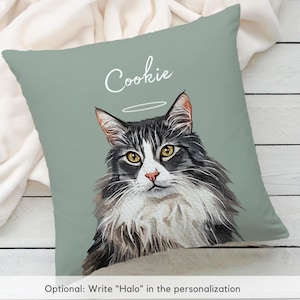 Puede incluir: Un coj&iacute;n decorativo con un retrato en acuarela de un gato con un halo. El gato tiene pelaje negro y gris, ojos amarillos y un hocico blanco. El nombre "Cookie" est&aacute; escrito encima del gato. El coj&iacute;n tiene un fondo verde salvia.