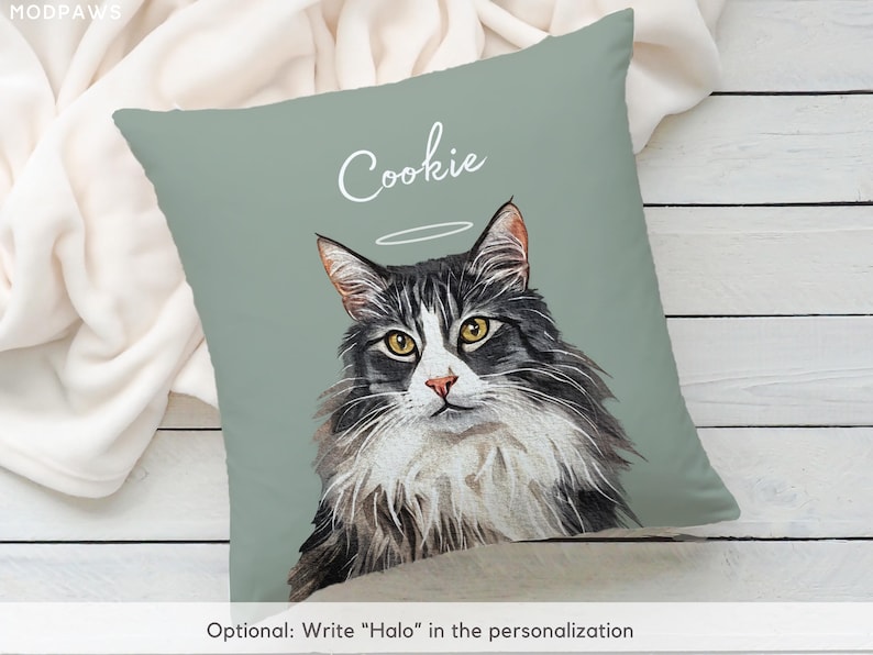 Puede incluir: Un coj&iacute;n decorativo con un retrato en acuarela de un gato con un halo. El gato tiene pelaje negro y gris, ojos amarillos y un hocico blanco. El nombre "Cookie" est&aacute; escrito encima del gato. El coj&iacute;n tiene un fondo verde salvia.