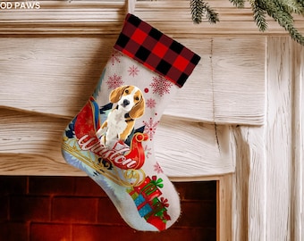 May include: A Christmas stocking featuring a red and black buffalo plaid cuff, a beige body with red snowflake patterns, and a graphic of a beagle sitting in a red sleigh. The name Winston is written in white script on the sleigh, with gift boxes below.