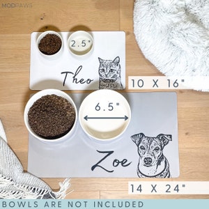 May include: Two pet food mats, one white and one grey, with pet portraits and names. The white mat is 25.4 x 40.6 cm, the grey mat is 35.6 x 61 cm. The bowls are not included. One bowl is 6.4 cm, the other is 16.5 cm.