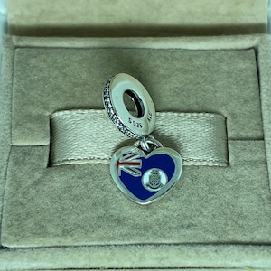 May include: Silver charm in the shape of a heart with the flag of the British Virgin Islands on one side and the territory's coat of arms on the other. The charm is attached to a silver bead with the inscription "S925 ALE".
