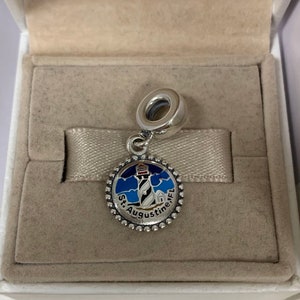 K&ouml;nnte beinhalten: Silberner Anh&auml;nger mit einem blauen, wei&szlig;en und roten Emaille-Leuchtturm-Design. Der Anh&auml;nger tr&auml;gt den Text "St. Augustine, FL" am Rand.