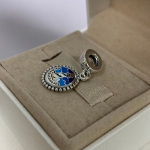 K&ouml;nnte beinhalten: Silberner Anh&auml;nger mit einem blauen und wei&szlig;en Emaille-Design eines Leuchtturms und dem Text "St. Augustine, FL".