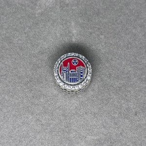 May include: Silver charm with a red, white, and blue enamel design of the Nashville skyline. The charm is surrounded by a circle of clear cubic zirconia stones.