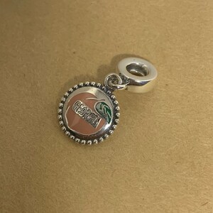 May include: Silver charm with a peach design and the word "Georgia" on it. The charm has a loop for attaching to a bracelet or necklace.