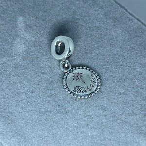May include: Silver charm with a star and the word "Bethlehem" engraved on a round disc.