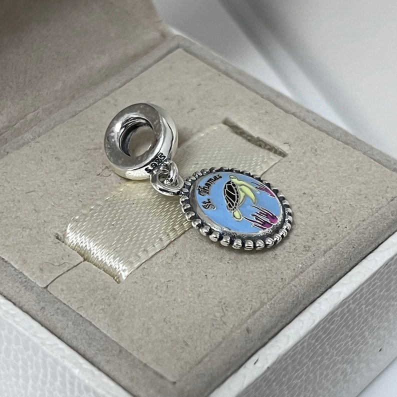 Puede incluir: Encanto de plata con un c&iacute;rculo de esmalte azul que presenta una tortuga marina y el texto "St. Thomas".