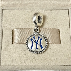 Op de afbeelding: Een zilveren bedel met een blauw en wit New York Yankees logo. De bedel is rond en heeft een parelrand.