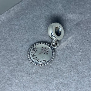 May include: Silver charm with a star and the words "Bethlehem" engraved on a round disc.