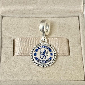 Op de afbeelding: Zilveren bedel met een blauw en gouden emaille Chelsea Football Club logo. De bedel toont een leeuw en de woorden "Chelsea Football Club".
