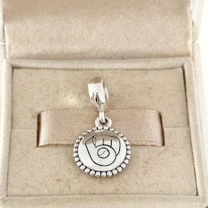 May include: A silver charm with a baseball glove and ball design. The charm is round with a beaded edge and hangs from a silver bail. The charm is displayed in a beige jewelry box.