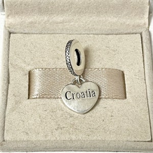 Puede incluir: Encanto de plata en forma de coraz&oacute;n con la palabra "Croacia" inscrita en &eacute;l. El encanto est&aacute; unido a una cuenta de plata con piedras de circonita c&uacute;bica transparentes.
