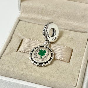 May include: Silver charm with a green four-leaf clover and horseshoe design. The charm is marked with "S925 ALE".